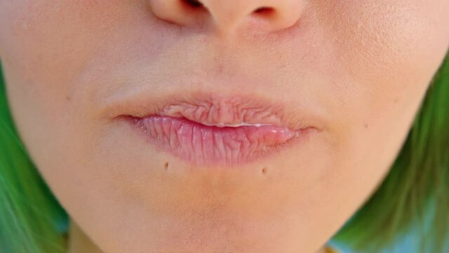 Girl with green hair eats yogurt from a spoon. Close up