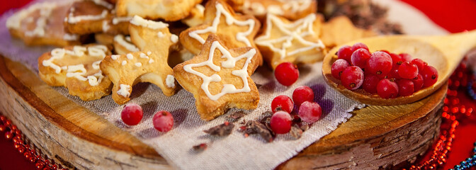 Christmas gingerbread cookies, chocolate and frozen berries, on a wooden stand, red background. Christmas and New Year concept.
