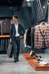 Shopping day. Young guy in modern store with new clothes. Elegant expensive wear for men