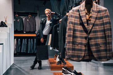 Fototapeta premium Weekend shopping. Young guy in modern store with new clothes. Elegant expensive wear for men