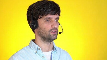Successful man in headset gesturing and talking on camera on a yellow background. Concept of technology and online communication.
