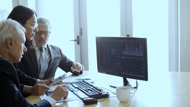 Group of investors watching stock market dynamics, looking and pointing at financial charts on pc monitor. Business and trading concept