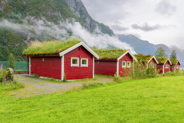Fototapeta na wymiar Traditional Norwegian red houses with a turf roof. Old farm hotel near Lake - norway