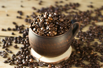 coffee beans are poured into a brown clay mug. coffee is poured into a Cup and scattered around on...