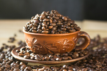 coffee beans are poured into a brown clay mug. coffee is poured into a Cup and scattered around on...