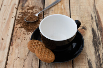 close up morning instant coffee with iron spoon and two biscuit cookies on a wooden table