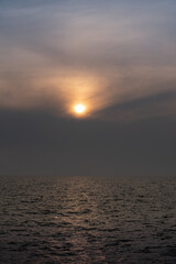 Fototapeta premium sun behind clouds or fog in the sea