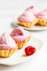 Mini cakes baskets with raspberry cream on white plate