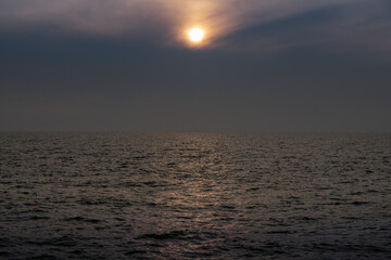 sun behind clouds or fog in the sea