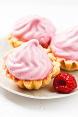 Mini cakes baskets with raspberry cream on white plate