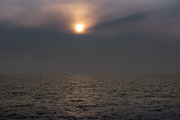 sun behind clouds or fog in the sea
