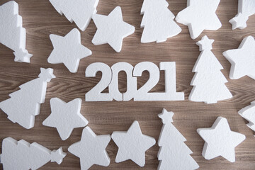 White 2021 new year number, stars and Christmas trees on wooden background