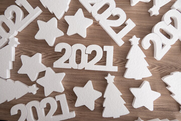 White 2021 new year number, stars and Christmas trees on wooden background