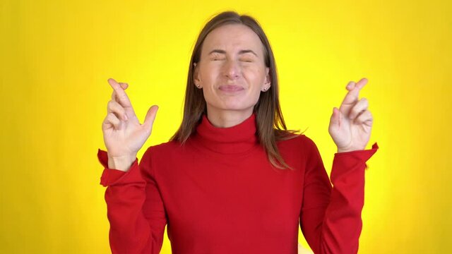 Young woman look camera bit lips hands folded in prayer beg about something good keep fingers crossed making wish isolated on yellow background in studio. 