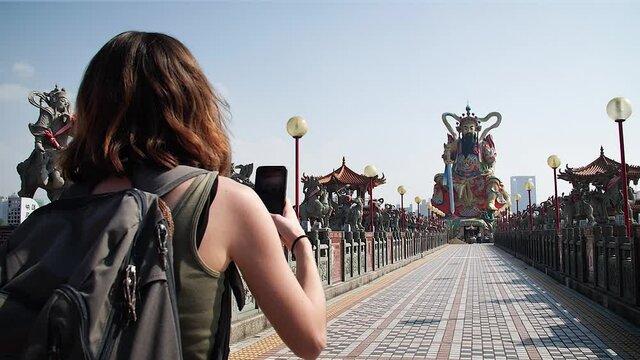 Girl taking photo with her mobile of Pagoda at Lotus Pond in Kaohsiung, Taiwan. Mid angle, parallax movement, slow motion, HD.