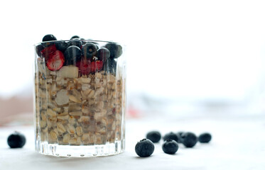 Breakfast, food, healthy eating and diet concept - close glass of granola oatmeal with chia, cranberry and american blueberries on table