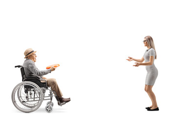 Elderly man in a wheelchair playing a game with a plastic disk with a young woman