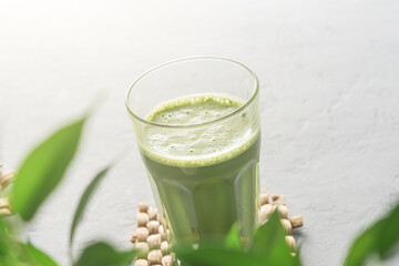 A tall glass of matcha tea on a gray concrete background.