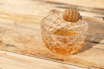 glass bowl with honey and honey dipper on a wooden table