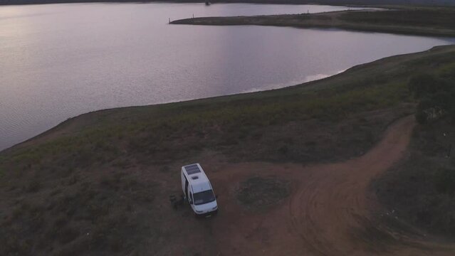 Drone panoramic aerial view of a camper van living vanlife at Minutos Dam in Arraiolos Alentejo at sunset, Portugal