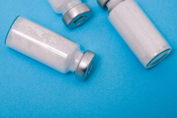 Naklejka premium Glass medical ampoule with a metal lid. Bottle of white powder. Antibiotic for the treatment of infections and diseases. Coronavirus vaccine. Healthcare and medicine