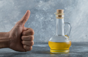 Obraz na płótnie Canvas Man gesturing thumb up to bottle of oil