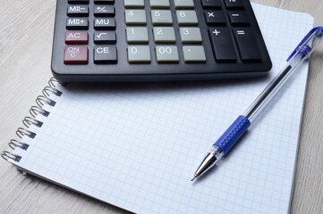 a ballpoint pen and a micro calculator lie on a squared notebook. close-up.