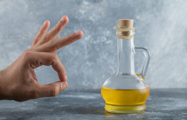 Obraz na płótnie Canvas Man gesturing ok with hand behind of bottle of oil