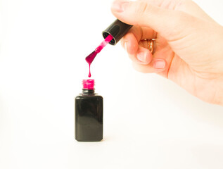 Naklejka premium Cropped view of woman holding opened bottle of pink nail polish isolated on beige