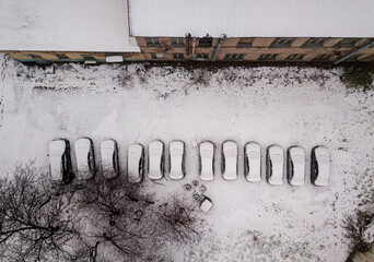 Aerial drone view. Snow-covered cars near the house.