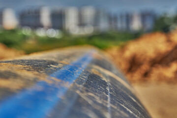 A plastic water pipe lies on the ground against the background of the city in the distance
