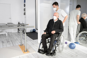 Male Nurse assisting a senior handicapped patient in wheelchair at rehabilitation center. High quality photo