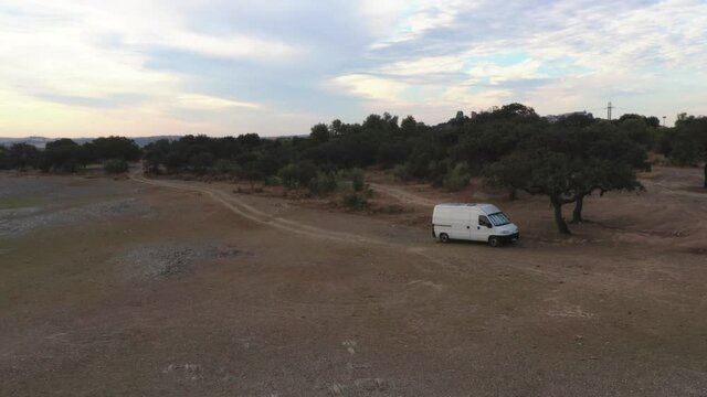 Drone aerial view of Camper van on an Alentejo dam lake landscape and under the shade of olive and cork trees, in Portugal