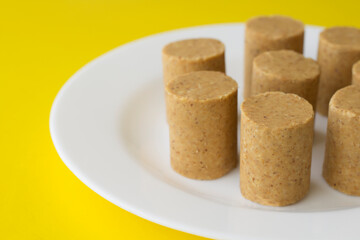 Um prato com várias paçocas (doces de amendoim) em uma mesa amarela.