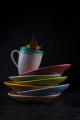 splash and splatter from a piece of sugar in a mug with coffee on a black background