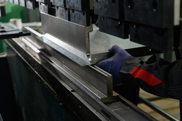 worker operating metal press machine at workshop.