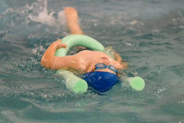 Toddler swimming training in the pool. Swimming training for a child. Development of children's sports. Strengthening baby's health.