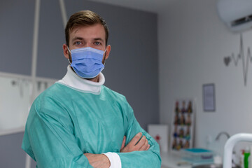 Fototapeta na wymiar Portrait of a handsome doctor in uniform with a face mask. 