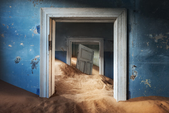 Abandoned building and the door being taken over by encroaching sand, Kolmanskop ghost town, Namib Desert