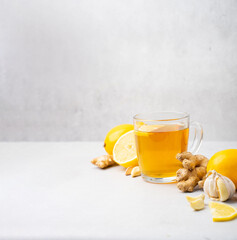 Hot herbal tea with ginger, garlic, lemon and honey vitamins C over grey background. Concept...
