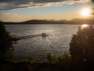Sunset on a quiet lake with deck chairs on a pontoon