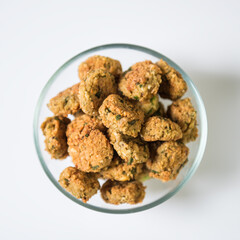 Baked homemade meatballs in a transparent bowl on a white background
