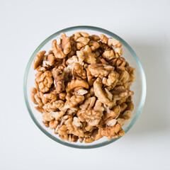 Walnuts in a transparent bowl on a white background