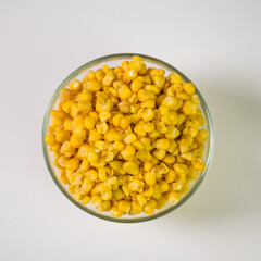 Tinned corn in a transparent bowl on a white background