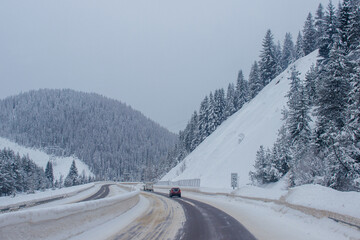Fototapeta na wymiar Snow-covered highway among the mountains, on the sides there are trees and trees in the snow. Winter landscape with snow-covered road, fir trees and mountains in Montana, America, 1-18-2020