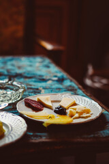 Close up. White plate with different types of cheese, salami and figs cut into thin slices on the dining table. Traditional Italian appetizer in Palermo, Sicily, Italy. European cuisine