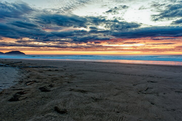 Golden sunrise across the ocean on a beach - 401572880
