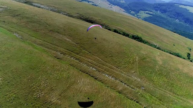 Aerial drone view during a paragliding flight from a mountain, breathtaking panorama. It feels like walking on the tip of the mountains, fun and adrenaline while flying