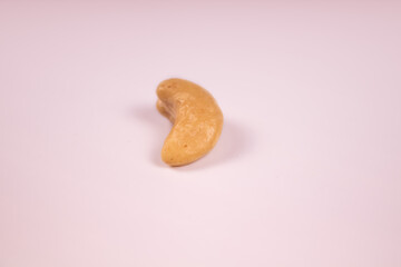 Peeled cashew kernels of ripe cashews in the center of a solid color background