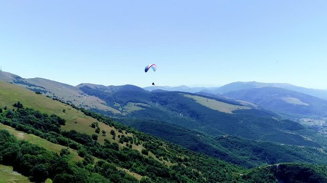 Aerial drone view during a paragliding flight from a mountain, breathtaking panorama. It feels like walking on the tip of the mountains, fun and adrenaline while flying